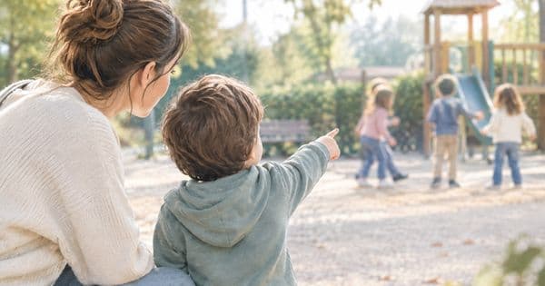 Dubbi sullo sviluppo? Mamma e figlio al parco osservano altri bambini che giocano. Una scena quotidiana che introduce il tema del confronto tra le tappe di crescita e quando consultare uno specialista dell'età evolutiva