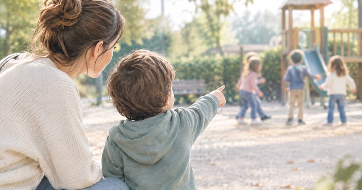 Dubbi sullo sviluppo? Mamma e figlio al parco osservano altri bambini che giocano. Una scena quotidiana che introduce il tema del confronto tra le tappe di crescita e quando consultare uno specialista dell'età evolutiva